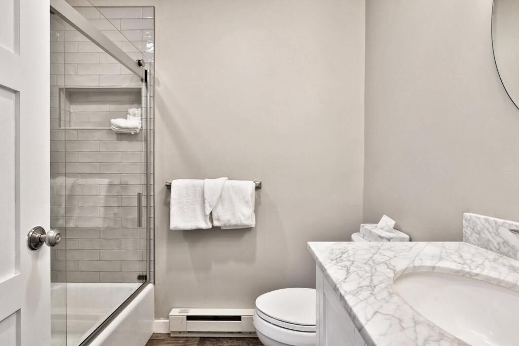 Un baño moderno con cabina de ducha de vidrio, lavabo de mármol y retrete.