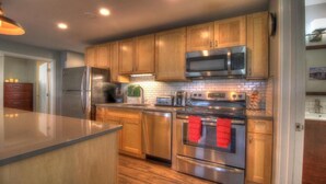 A modern kitchen with wooden cabinets, stainless steel appliances, and a central island.
