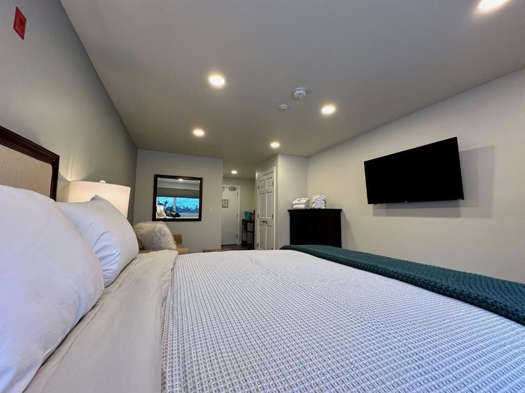 A hotel room with a bed, a television mounted on the wall, and a window with a view.