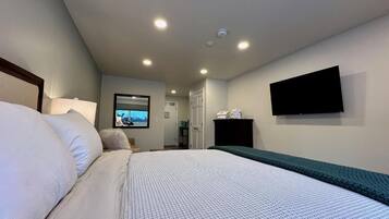 A hotel room with a bed, a television mounted on the wall, and a window with a view.