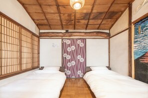 A traditional Japanese room with two beds, wooden flooring, a tatami mat entrance, and a shoji screen with floral patterns. - Sanada Maru (Kaizuka)