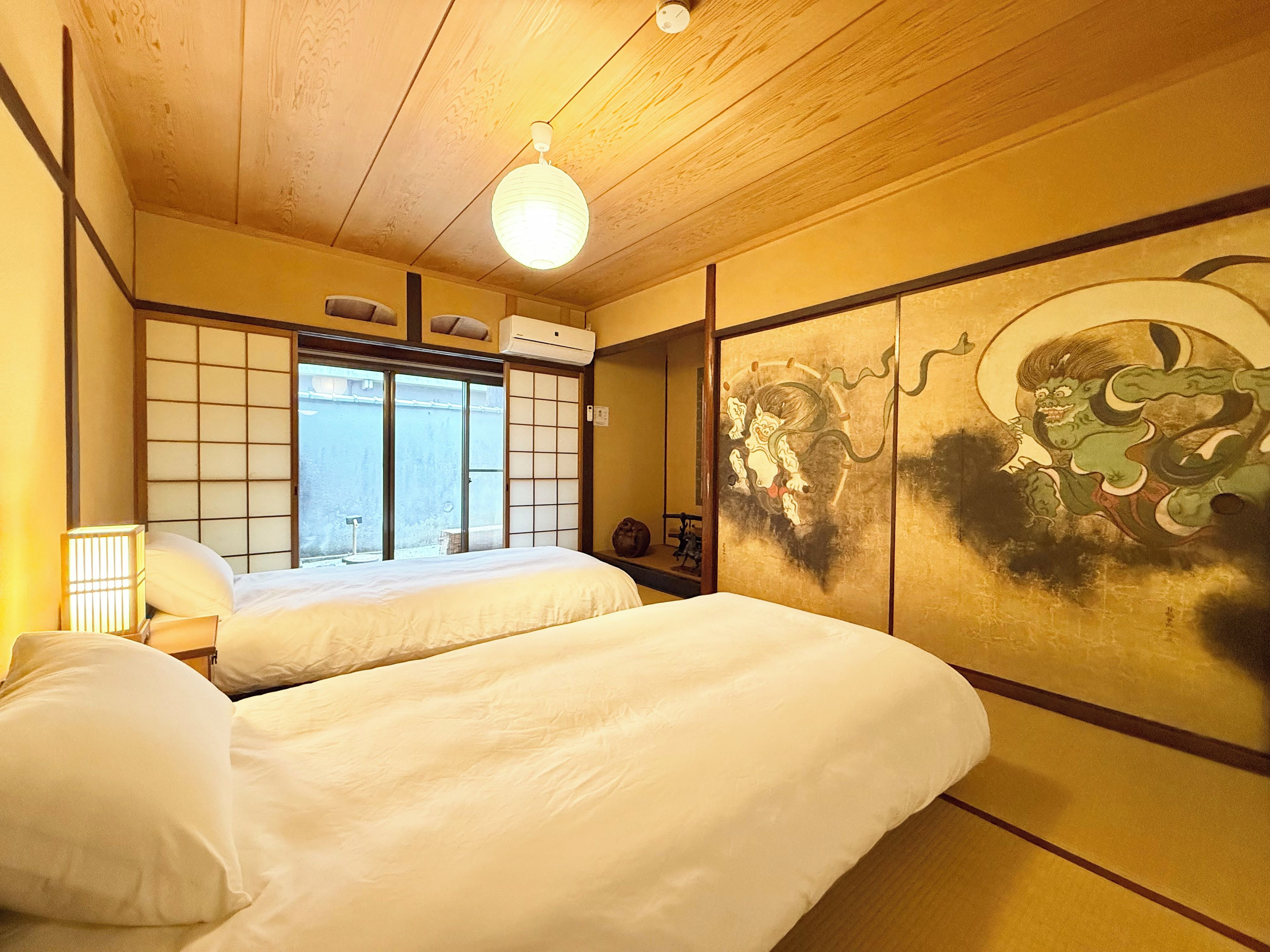 A traditional Japanese-style room with tatami flooring, a shoji screen, and a futon bed.
