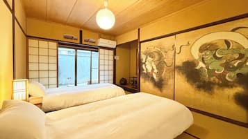 A traditional Japanese-style room with tatami flooring, a shoji screen, and a futon bed.