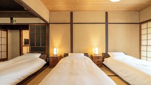 Una habitación tradicional japonesa con tres camas individuales, suelo de madera y puertas correderas shoji.