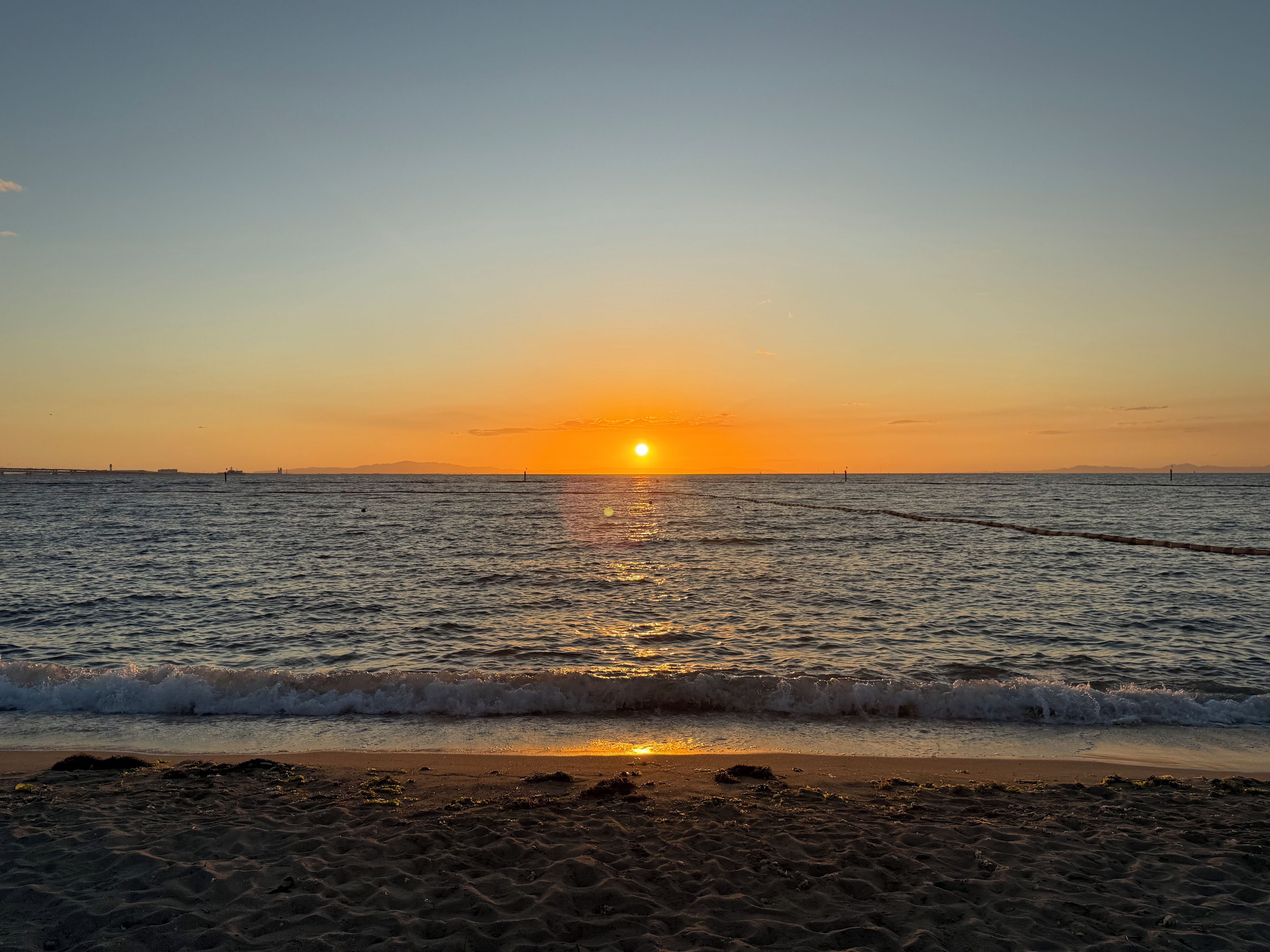 A beach at sunset with waves gently lapping the shore.