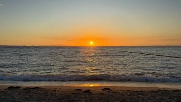 A beach at sunset with waves gently lapping the shore.