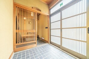 Una habitación japonesa tradicional con suelo de tatami, una puerta corredera con marco de madera y un mamparo shoji.
