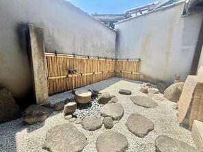 A courtyard with a bamboo fence, large rocks, and a concrete wall. - Sanada Maru (Kaizuka)