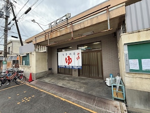 A building with a signboard, a bicycle parking area, and a small outdoor seating area. - Sanada Maru (Kaizuka)