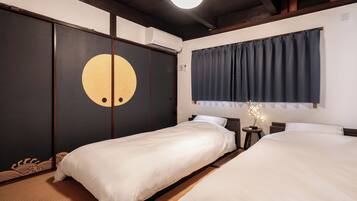 A hotel room with two beds, a large circular design on the wall, a ceiling fan, and a window with curtains.