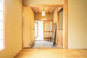 Un pasillo estrecho con suelo de madera, una puerta corredera y una lámpara.