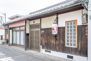 A traditional Japanese building with a wooden exterior, a tiled roof, and a large window with a grid pattern. - Sanada Maru (Kaizuka)
