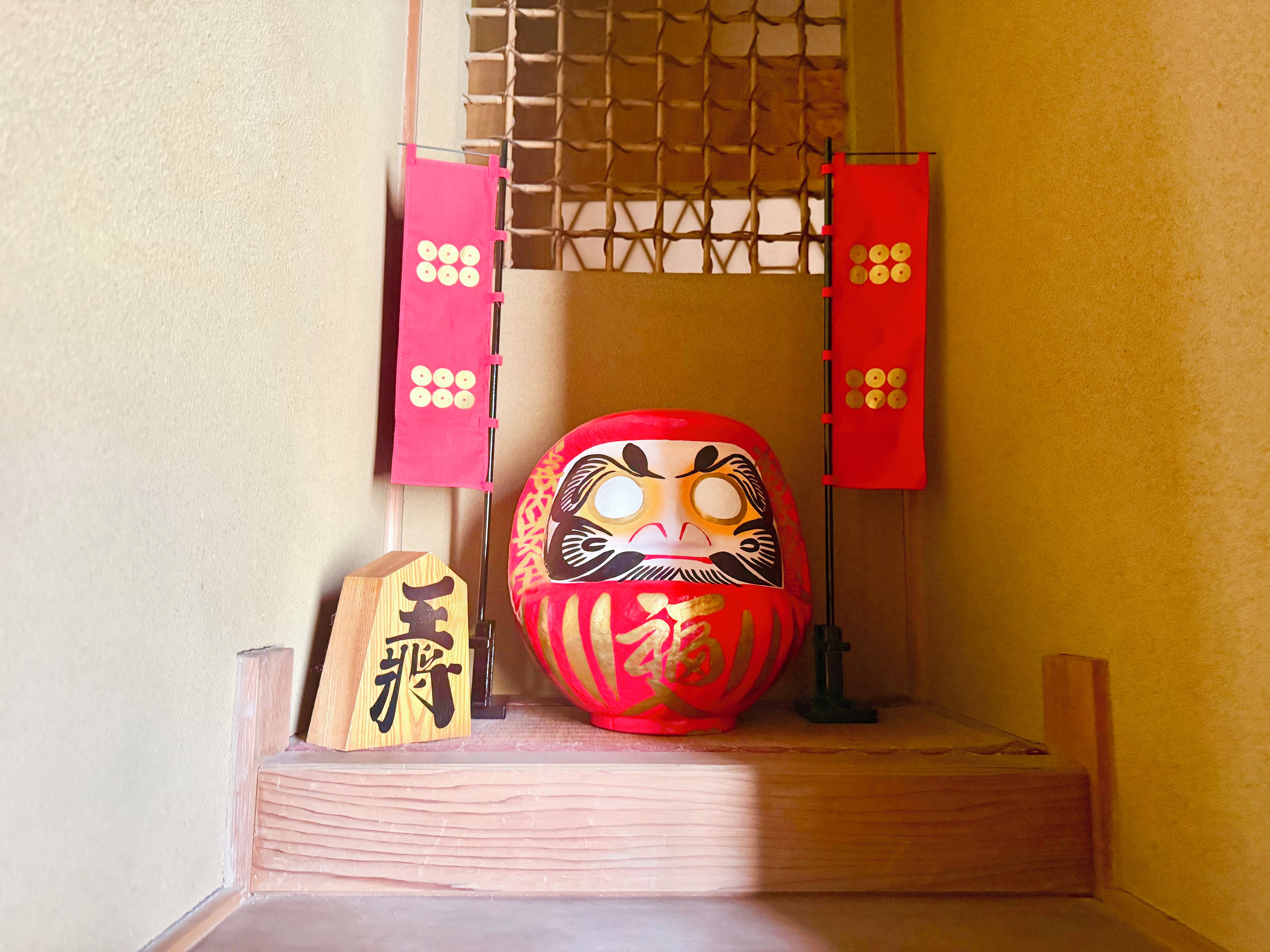A traditional Japanese room with tatami flooring, a shoji screen, and a decorative red and gold object.