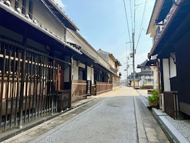 A traditional Japanese street with wooden buildings, a clear sky, and a paved road.