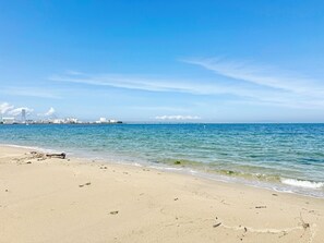 A beach with a clear view of the ocean and distant buildings. - Sanada Maru (Kaizuka)