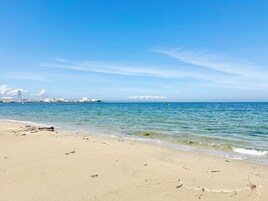 A beach with a clear view of the ocean and distant buildings.