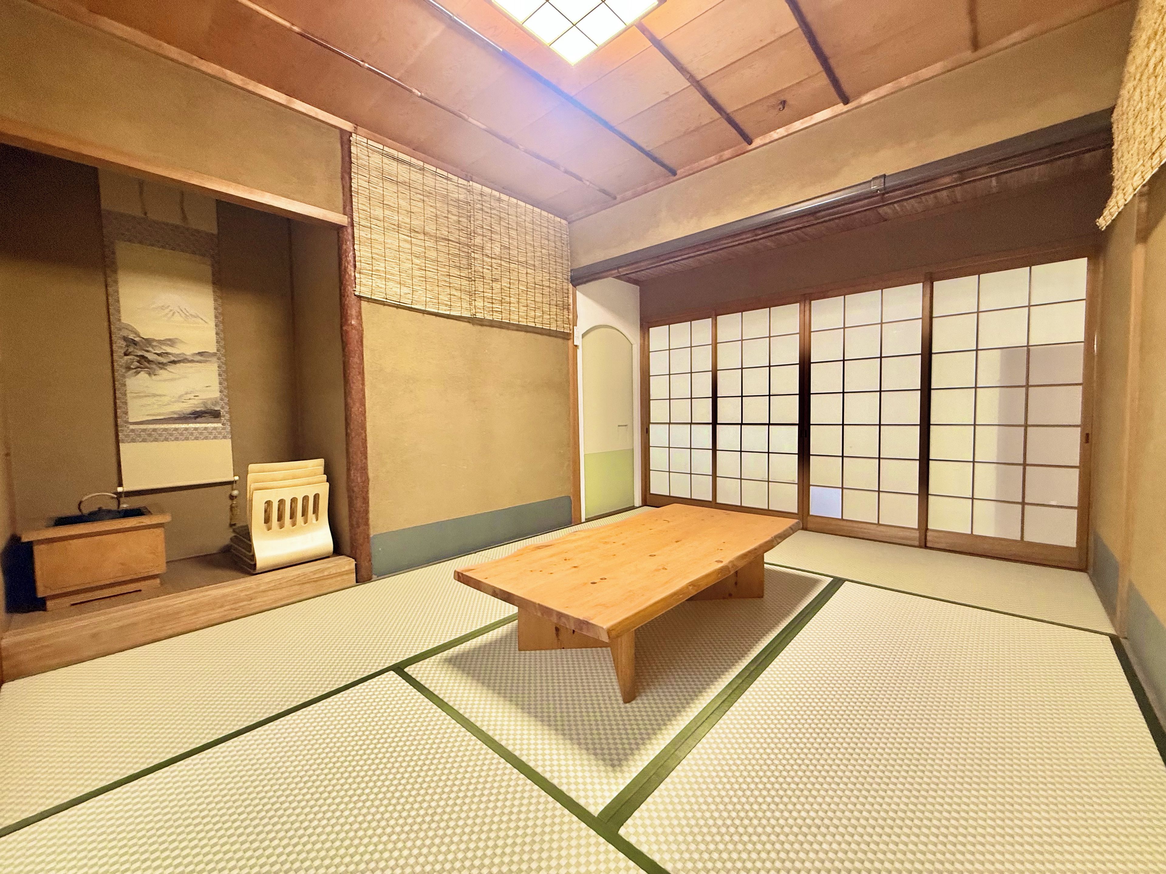 A traditional Japanese room with tatami flooring, a wooden table, a low bench, and shoji screens.
