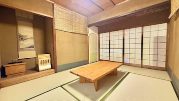 A traditional Japanese room with tatami flooring, a wooden table, a low bench, and shoji screens.