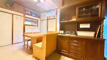 A room with a wooden table, chairs, a cabinet with drawers, a window, and a ceiling light fixture.