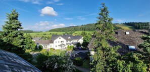 Un grand bâtiment blanc, doté d’un toit en pente, entouré de verdure et surplombé d’un ciel dégagé.