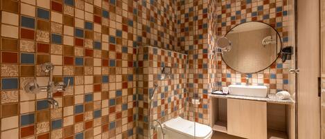 A bathroom with a tiled shower wall, a toilet, a sink, and a mirror.