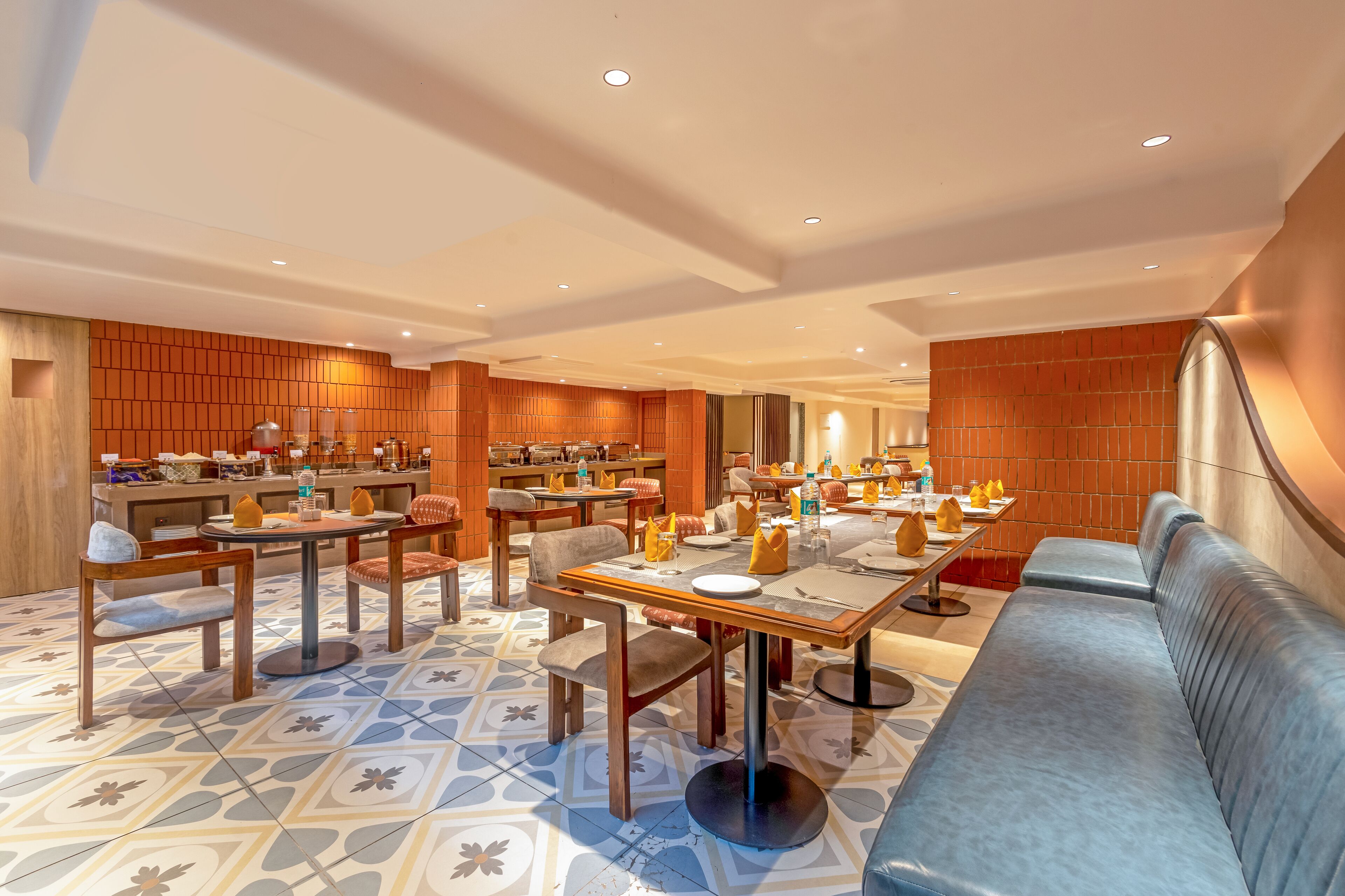 Un espace repas moderne avec plusieurs tables et chaises, un canapé et un sol à motifs.