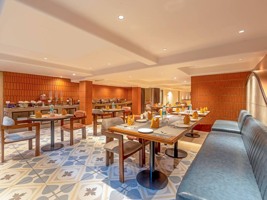 Un espace repas moderne avec plusieurs tables et chaises, un canapé et un sol à motifs.