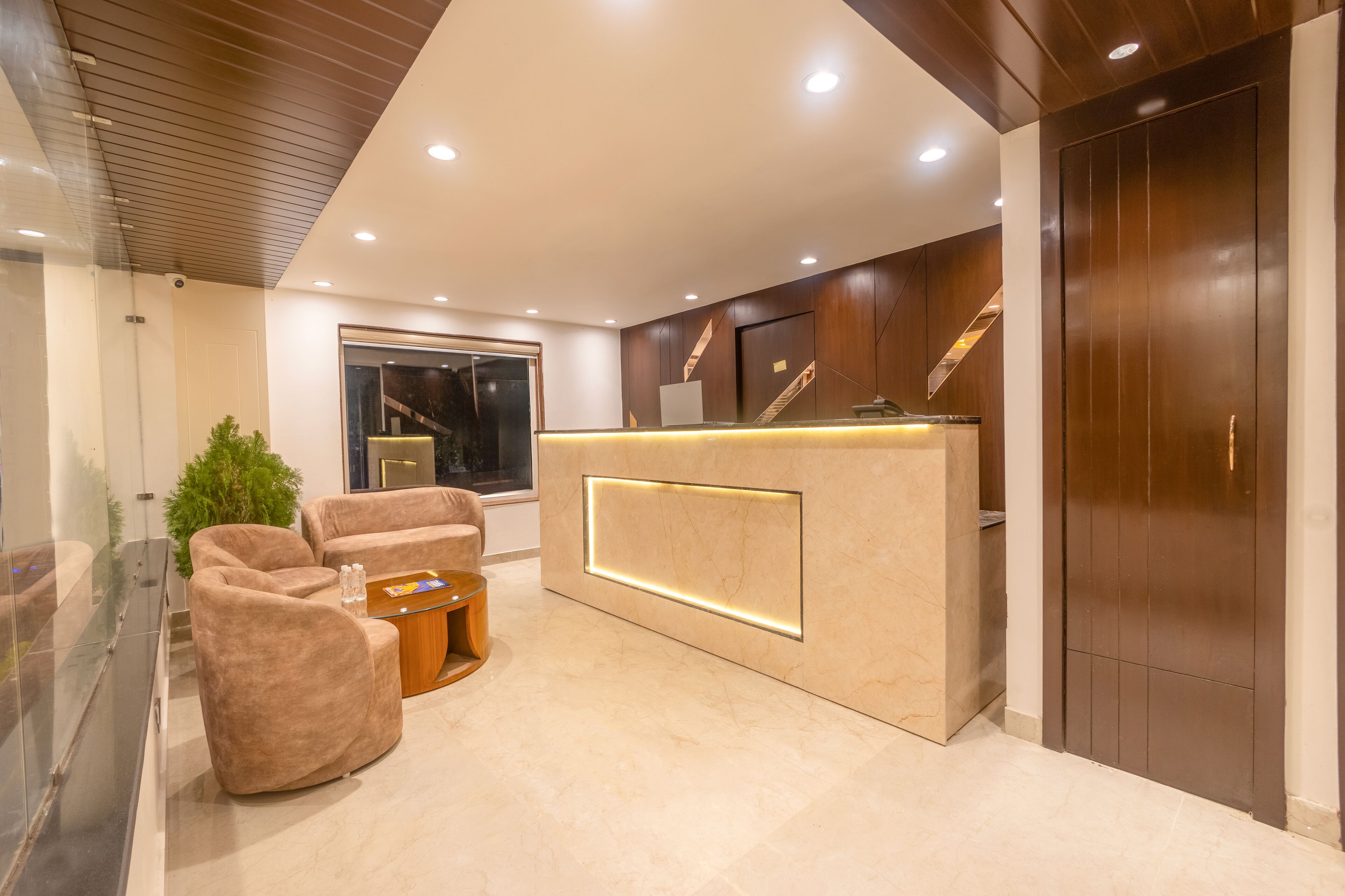 A modern reception area with a marble reception desk, plush seating, and a staircase.