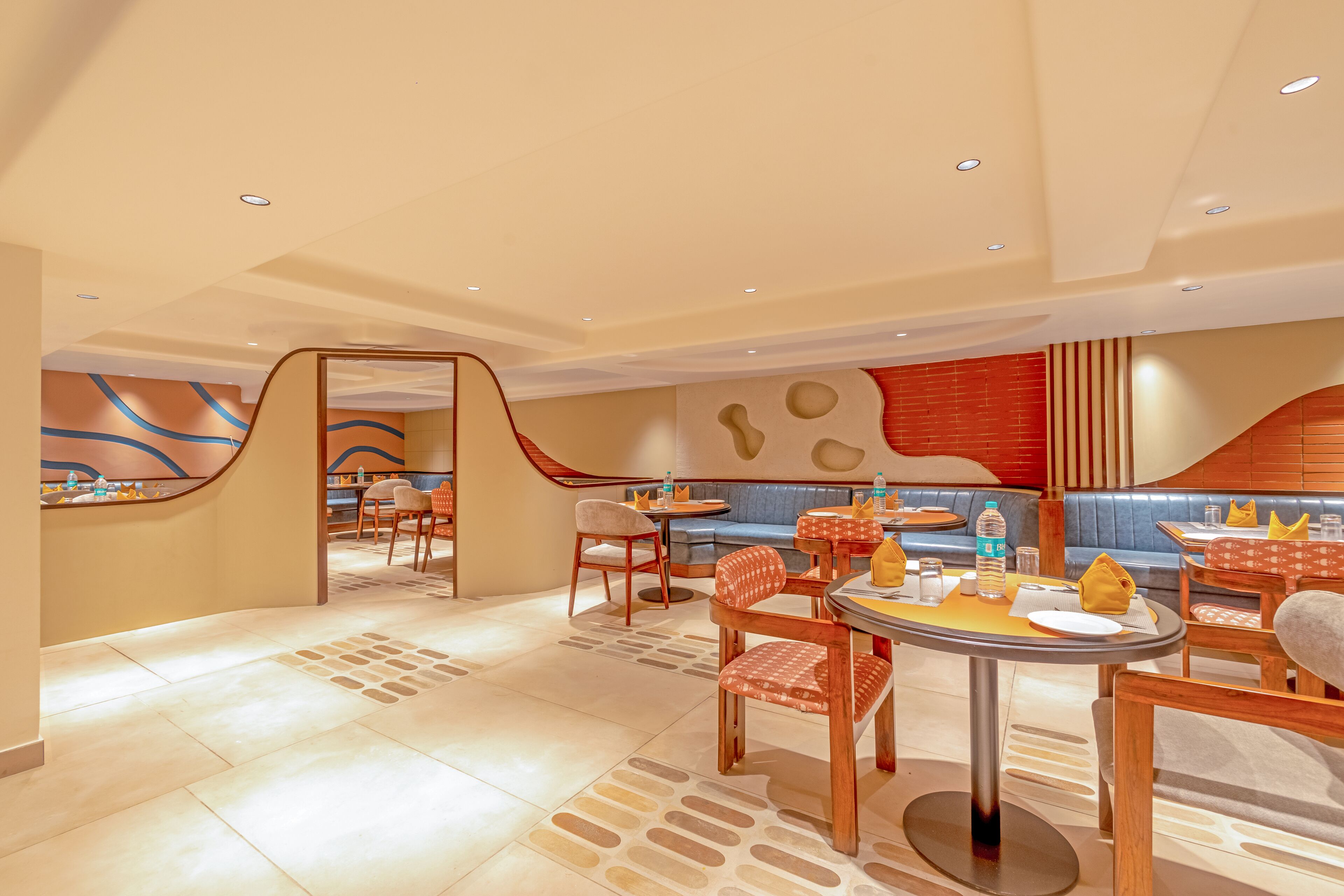 A modern restaurant with a curved wall design, seating areas, and a central round table.