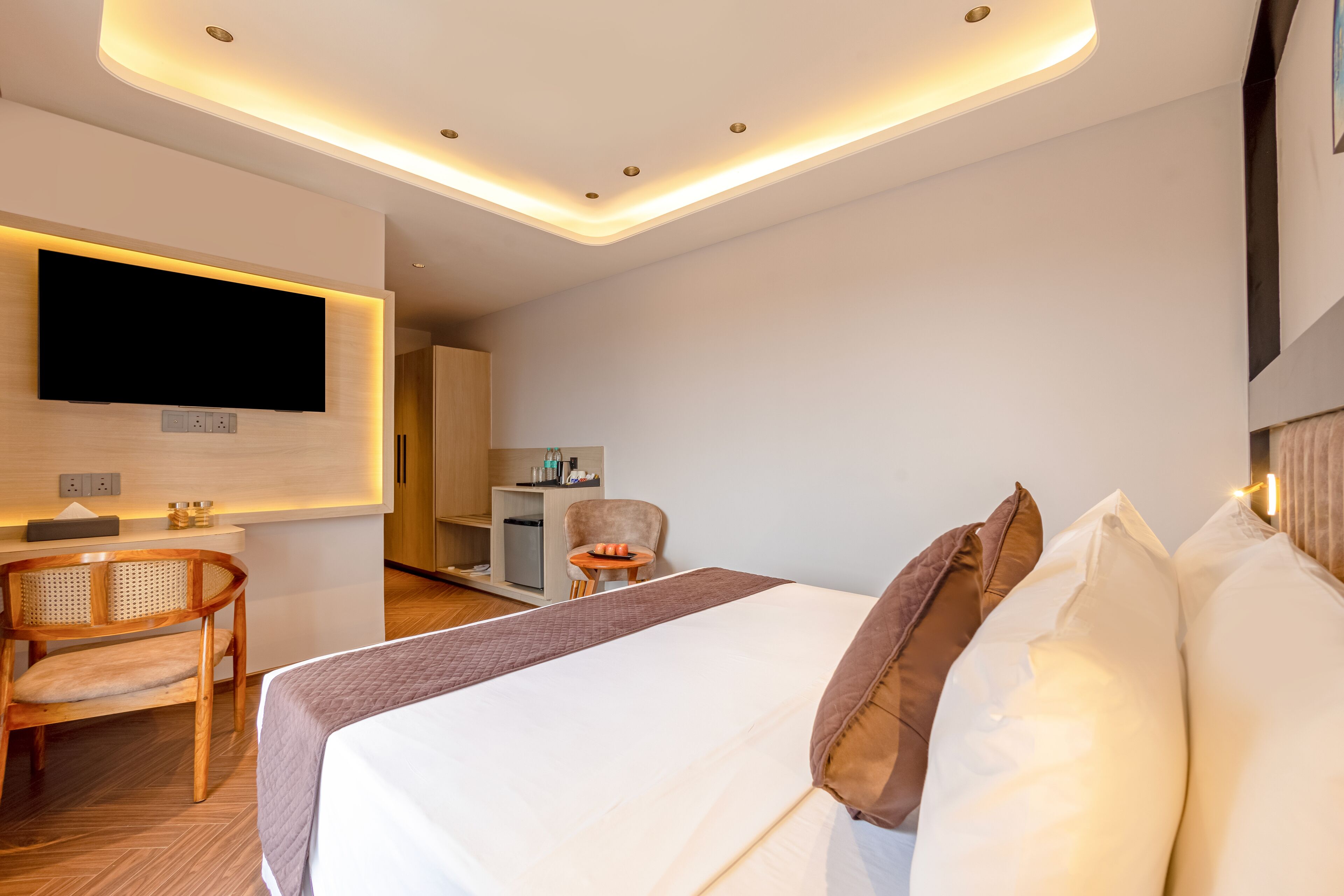 Una habitación de hotel moderna con una cama grande, un escritorio, una silla y un televisor fijado a la pared.