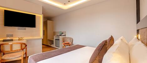 Una habitación de hotel moderna con una cama grande, un escritorio, una silla y un televisor fijado a la pared.
