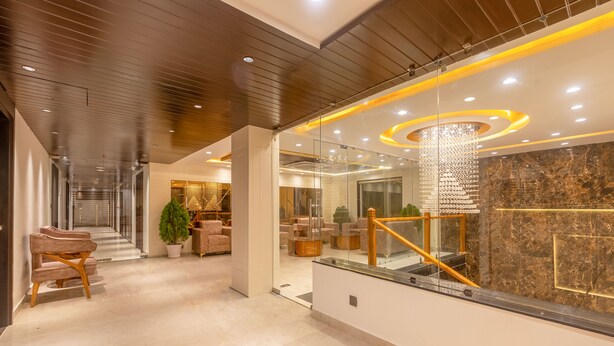Un hall d’hôtel moderne avec un sol en marbre, un plafond en bois et un escalier en verre.