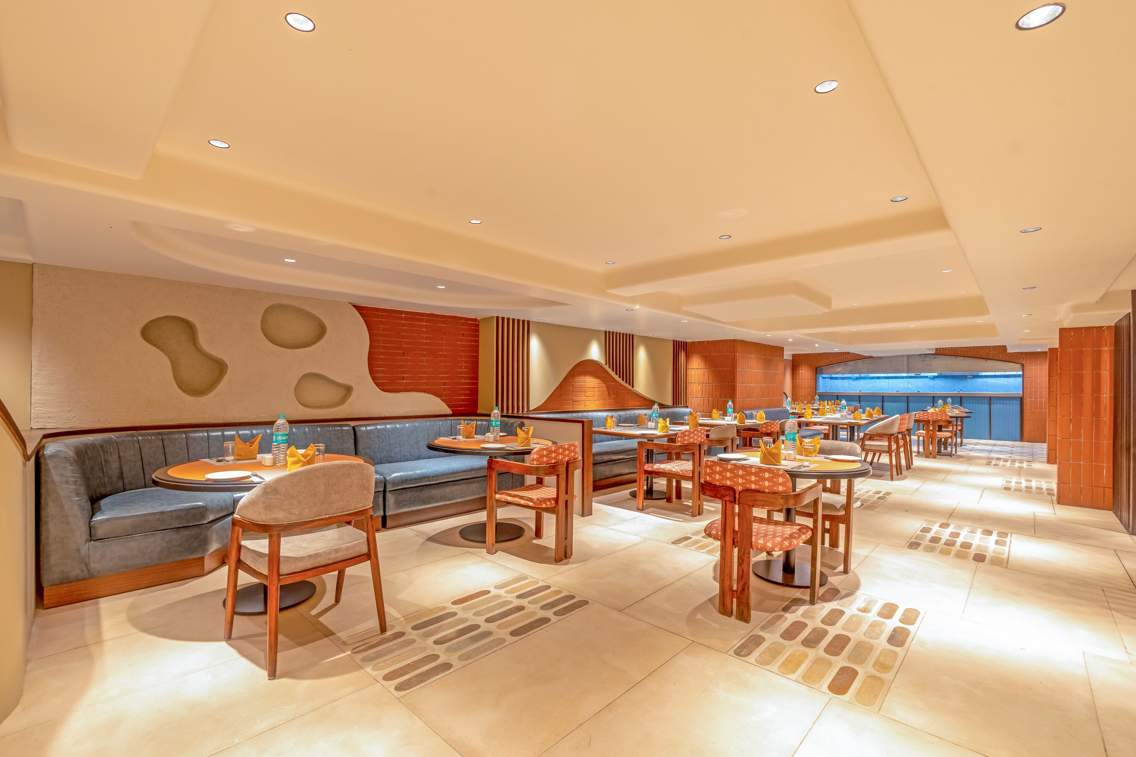 Un restaurante moderno con mesas redondas y asientos acolchados, que ofrece vistas al mar.