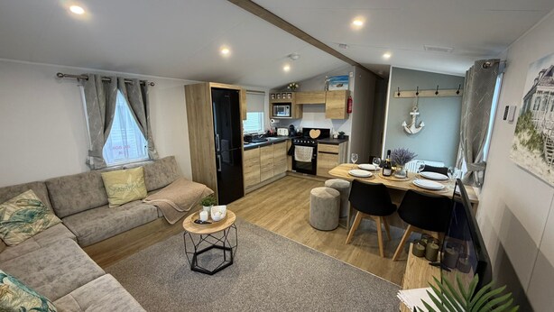 Un salon moderne avec un canapé, une table basse et un coin repas avec une table dressée pour quatre personnes.