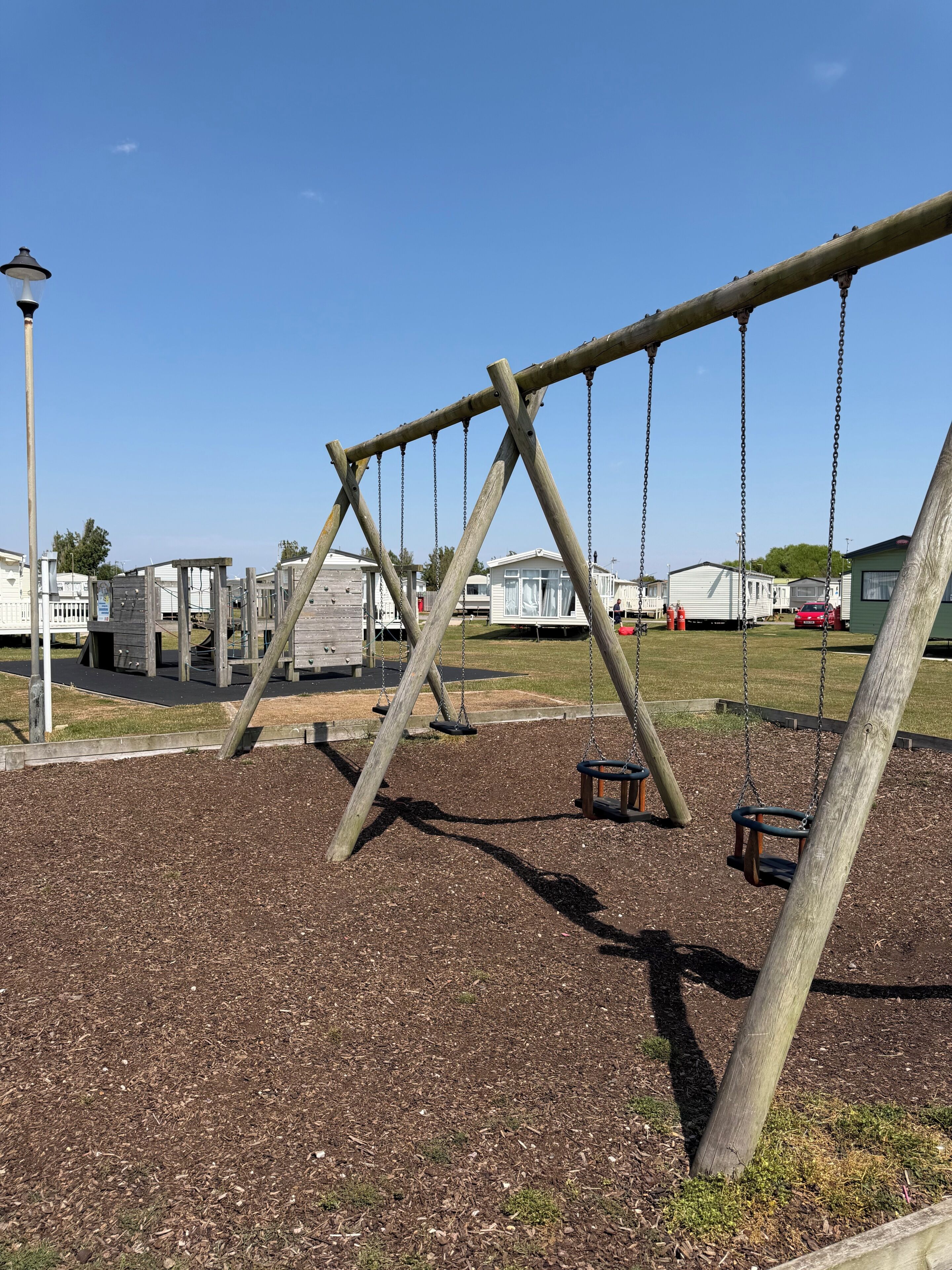 A playground with swings and a wooden structure.