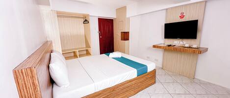 A modern hotel room with a bed, wooden headboard, a TV mounted on the wall, and a red door.