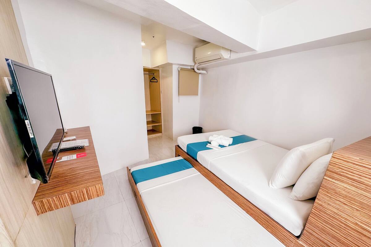 Ein Hotelzimmer mit einem Bett, einem Fernseher, einem Holztisch und einem Kleiderschrank.
