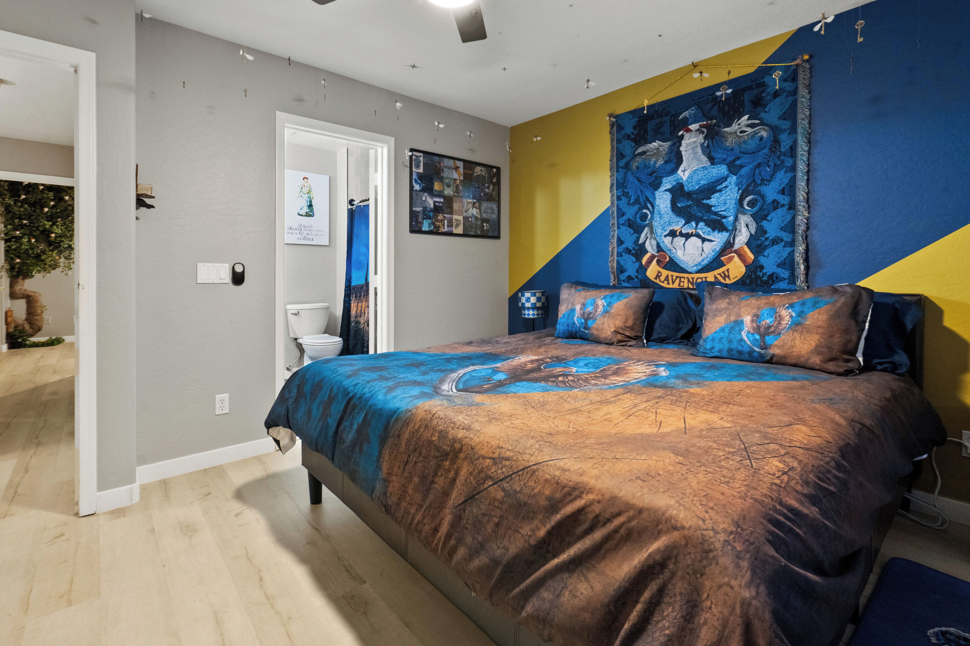 Une chambre à coucher avec un lit, une porte, un mur orné d’une tapisserie et une petite table.