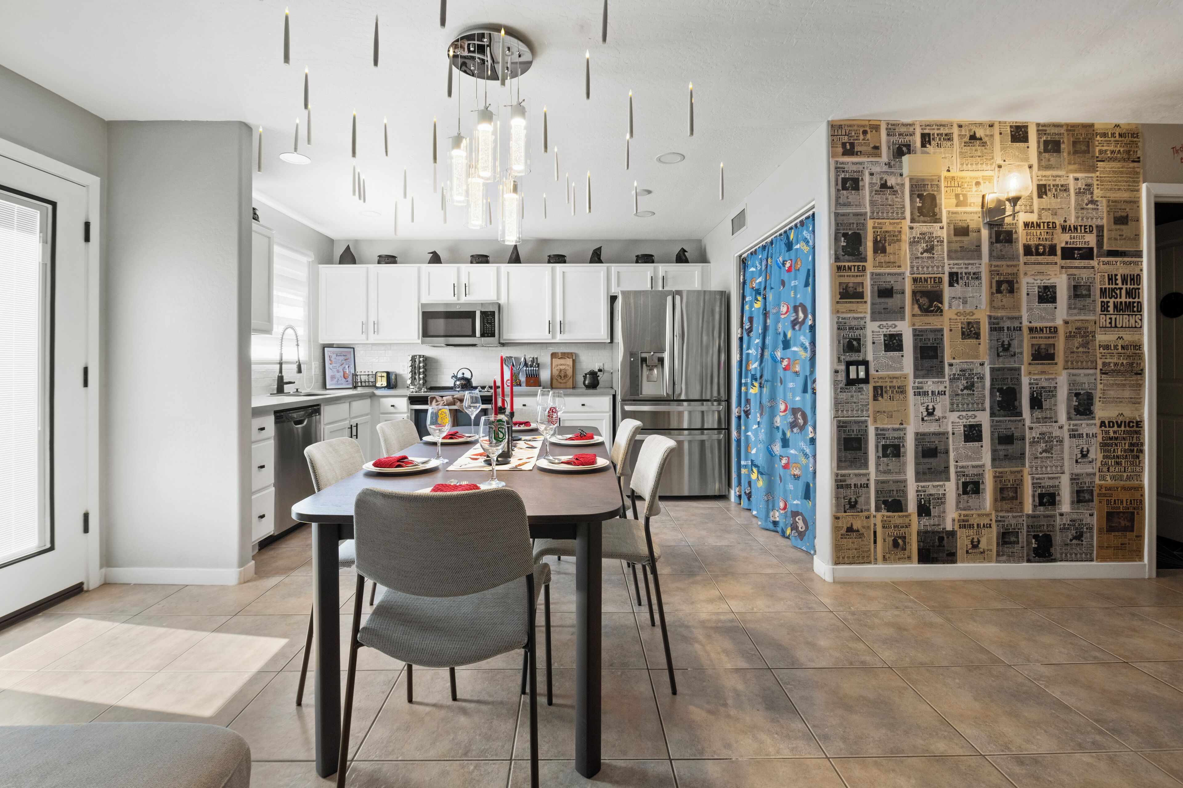 Une cuisine moderne avec des meubles blancs, un réfrigérateur en acier inoxydable et un coin repas avec une table dressée pour quatre personnes.