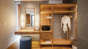 Ein modernes Badezimmer mit einem Holzbadezimmerhocker, einem Spiegel und einem eingebauten Kleiderschrank mit aufgehängter Kleidung.