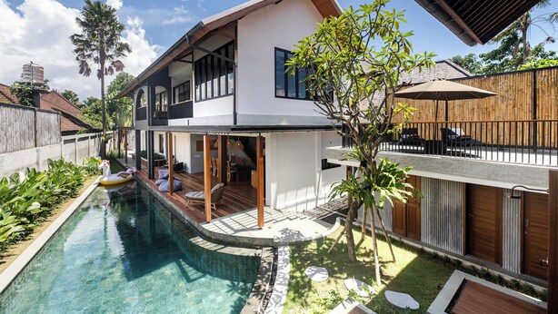 Ein modernes, zweistöckiges Haus mit Swimmingpool, Außenbereich mit Sitzgelegenheiten und Holzzaun.