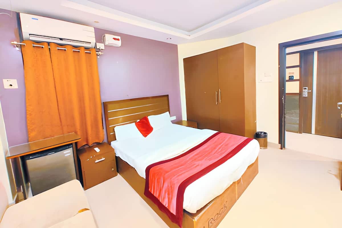 Habitación de hotel con cama, armario, aire acondicionado, mesita de noche y un mueble pequeño.