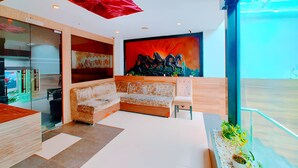 A modern living room with a sofa, a coffee table, and a red abstract painting. - Hotel Royal Castle Lucknow (Lucknow)