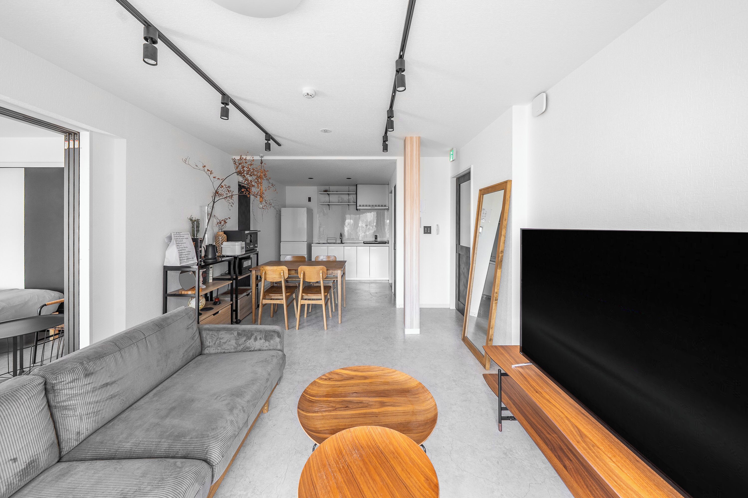 A modern living room with a sofa, coffee table, TV, and dining area.