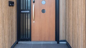 Una puerta de madera con marco negro, un pomo y tres aberturas circulares.