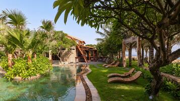 A pool area with a stone structure, lounge chairs, and lush greenery.