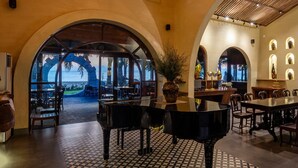 A spacious lobby with a grand piano, large arched windows, and a patterned floor. - Sun Village Beach Resort (Hoa Hiep)