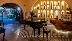 A lobby with a patterned floor, a piano, a reception desk, and a wall of arched windows with decorative items. - Sun Village Beach Resort (Hoa Hiep)