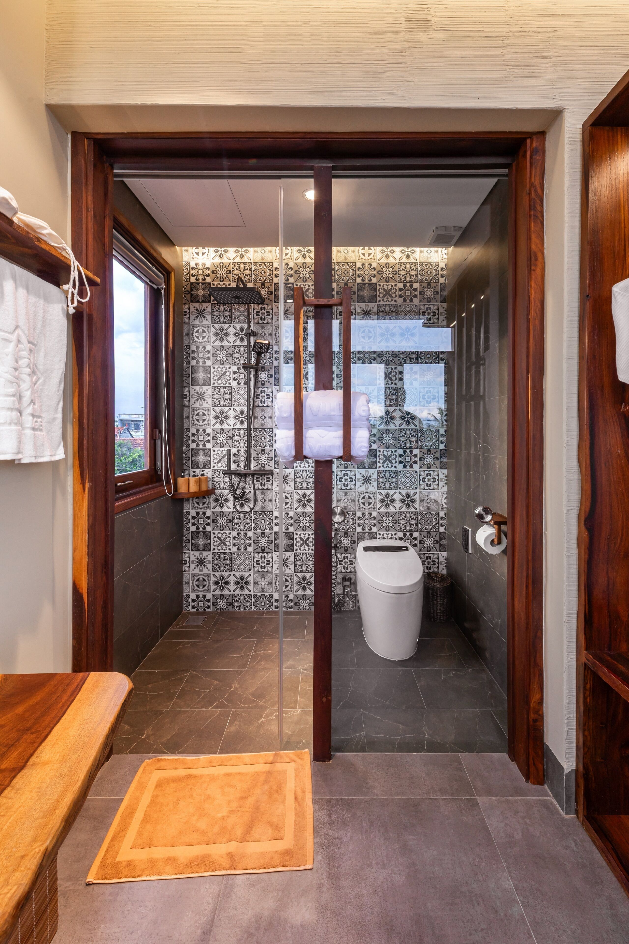 A modern bathroom with patterned tiles, a shower, and a toilet.