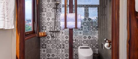 A modern bathroom with patterned tiles, a shower, and a toilet.